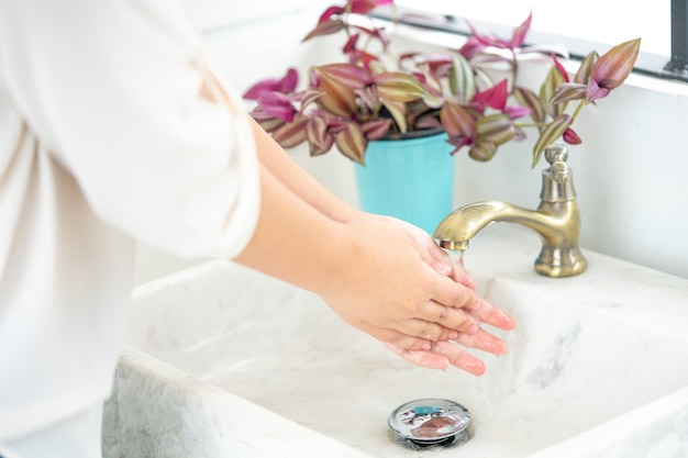 La main de la femme va ouvrir le robinet pour se laver les mains. Maintenir la propreté