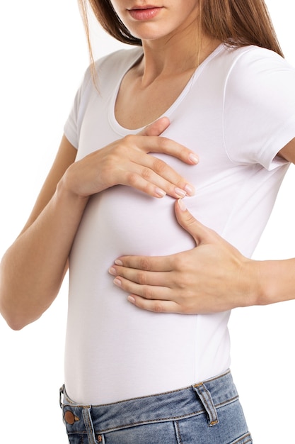 Main de femme vérifiant des bosses sur sa poitrine pour des signes de cancer du sein sur fond gris. Concept de soins de santé. Photo de haute qualité