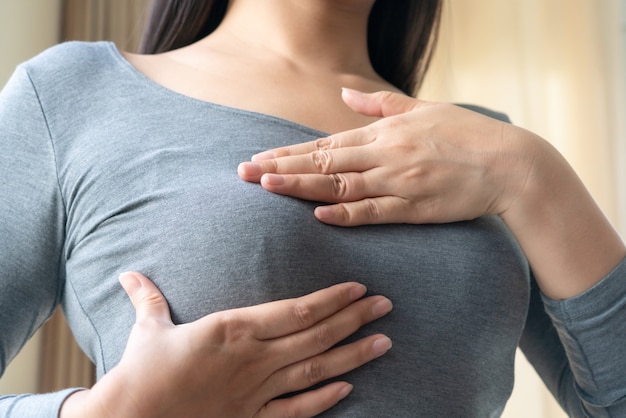 Main de femme vérifiant des grumeaux sur sa poitrine pour des signes de cancer du sein. Concept de soins de santé pour les femmes.