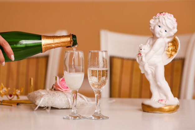 La main de la femme verse le champagne de mariage dans des verres à partir d'une bouteille lors d'une célébration, d'un mariage.