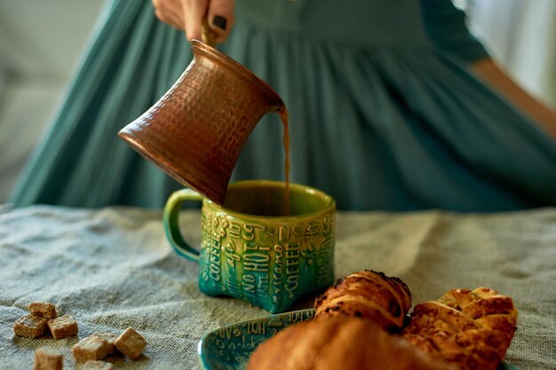 La main d'une femme verse du café infusé dans la simplicité de TurkRustic