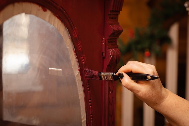 Main de femme vieillissant des ornements sculptés à la main d'une porte d'armoire en bois massif antique de couleur rose Donner une nouvelle vie à de vieux trucs Restauration à la main de vieux meubles