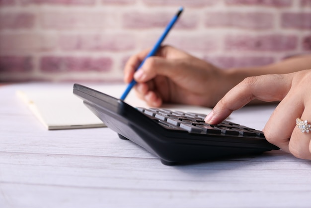 Main de femmes à l'aide de la calculatrice sur le bureau.