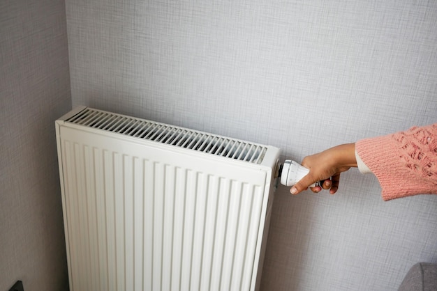 Main de femmes ajustant la température d'un radiateur