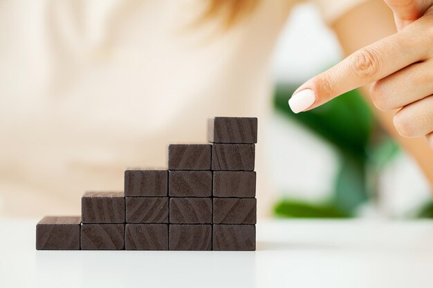 La main des femmes plie des cubes en bois noirs formant des escaliers.