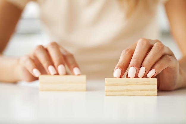 La main des femmes tient deux blocs de bois avec une place pour le texte