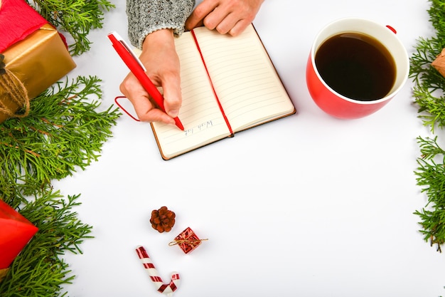 La main de la fille écrit les souhaits du nouvel an. Fille écrit un stylo sur un morceau de papier souhaits de Noël.