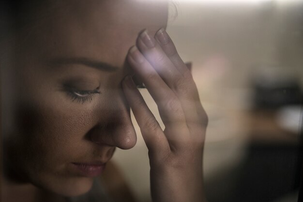 Photo main de fille mélancolique et triste à la fenêtre