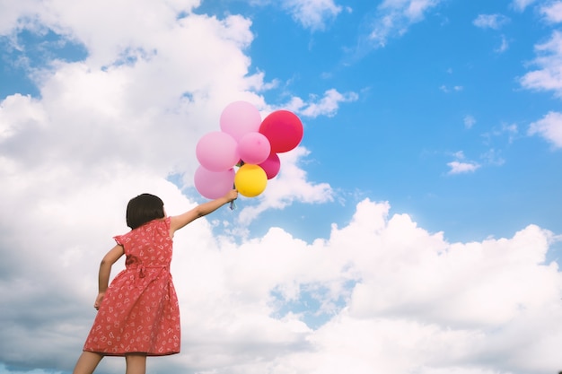 Main de fille tenant des ballons multicolores fait avec, concept de joyeux anniversaire en été