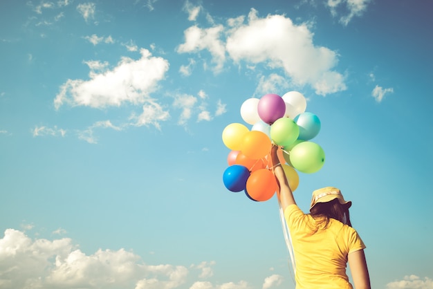 Main de fille tenant des ballons multicolores