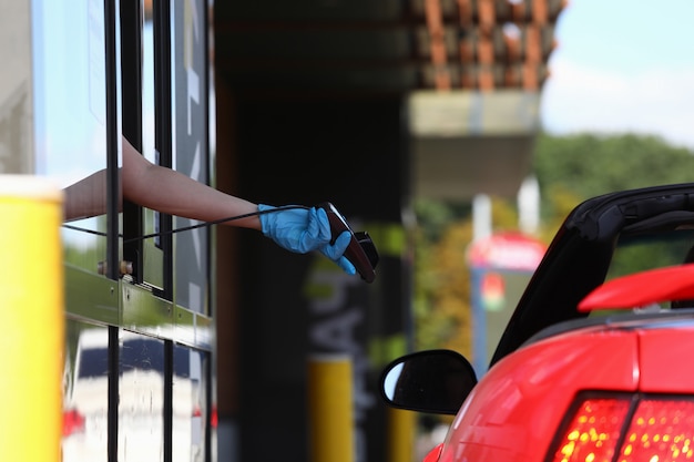 La main gantée tient le terminal de point de vente et le tend vers la voiture