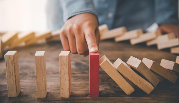 Main en gros plan La main d'un homme d'affaires qui arrête ou empêche la chute d'un bloc. Concept de protection contre les risques, Élimine le risque