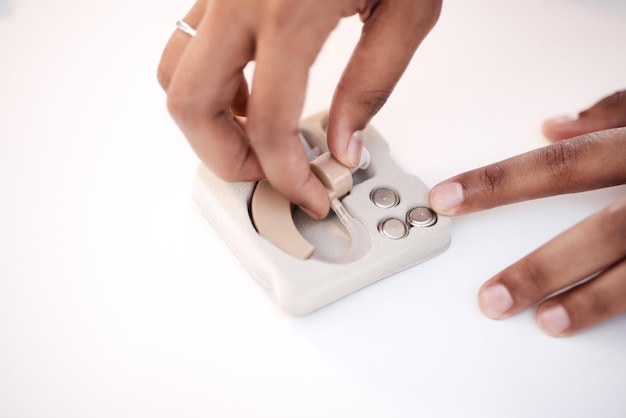 Main handicapée ou femme noire avec implant ou appareil sourd sur une table de bureau dans une clinique de soins de santé Technologie médicale et fille médecin pour l'assurance médicale aide auditive ou communication à l'hôpital