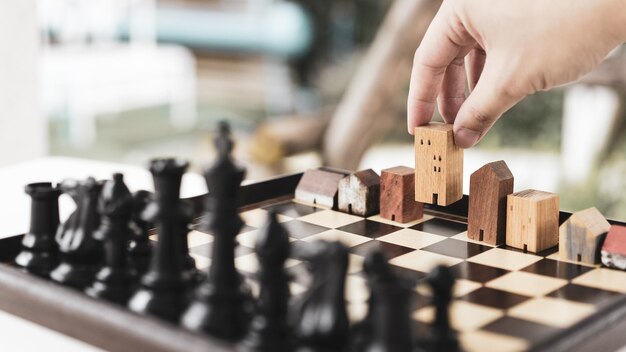 Photo la main d'un homme d'affaires déplaçant les échecs pour construire et construire des modèles dans un jeu d'échecs