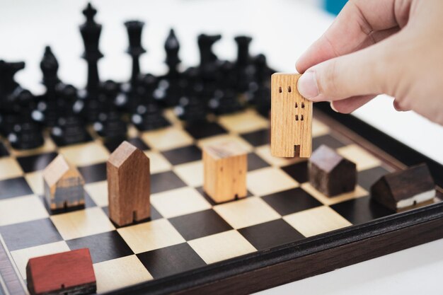 Photo la main d'un homme d'affaires déplaçant les échecs pour construire et construire des modèles dans un jeu d'échecs