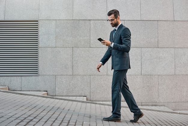 Main d'homme d'affaires élégant tenant et utilisant un téléphone intelligent à l'extérieur