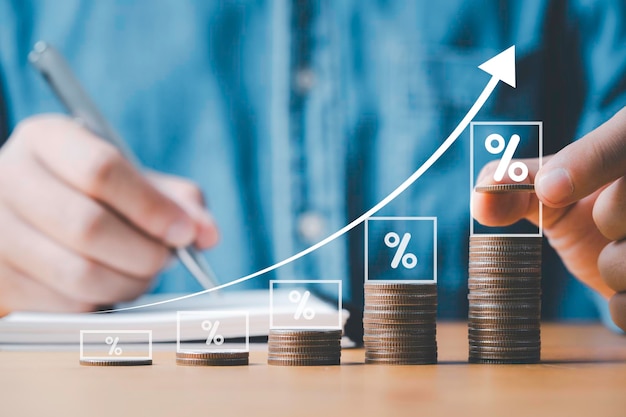 Main d'homme d'affaires empilant des pièces avec un graphique croissant virtuel et un pourcentage pour le bénéfice d'investissement des entreprises et le concept de croissance de l'économie de dividende de dépôt