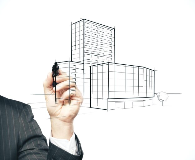 Main d'homme d'affaires avec le gratte-ciel de dessin de stylo