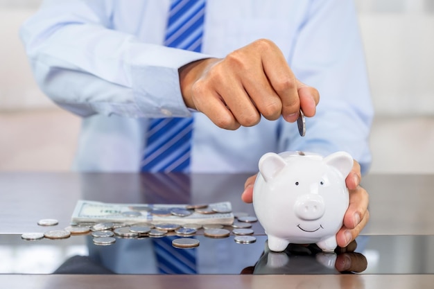 Photo main d'homme d'affaires mettant la pièce dans la tirelire bleue économiser de l'argent pour le futur plan d'investissement et le concept de fonds de retraite