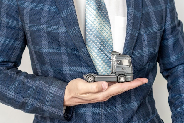Main d'homme d'affaires protégeant la voiture sur le concept d'assurance camion jouet camion L'inscription sur l'affiche est une assurance
