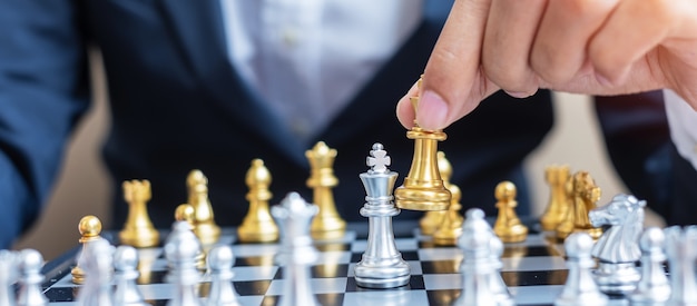 Main d'homme d'affaires se déplaçant or Chess King figure au cours de la compétition d'échecs.