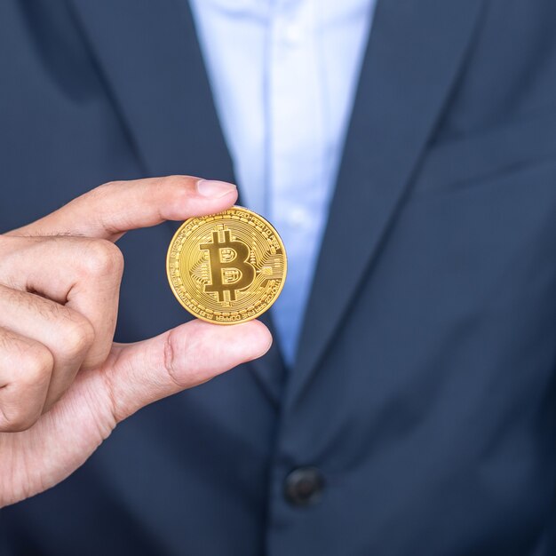 Main d'homme d'affaires tenant la crypto-monnaie Golden Bitcoin (BTC), Crypto est de l'argent numérique au sein du réseau blockchain, est échangé à l'aide de la technologie et de l'échange Internet en ligne. Notion financière