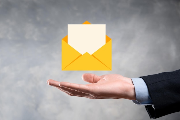 Main d'homme d'affaires tenant l'icône d'e-mail Contactez-nous par e-mail de newsletter et protégez vos informations personnelles contre les spams Centre d'appels du service client contactez-nous concept