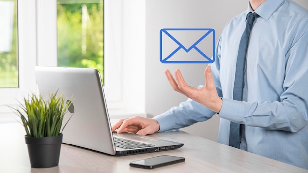 Main d'homme d'affaires tenant l'icône d'e-mail Contactez-nous par e-mail de newsletter et protégez vos informations personnelles contre les spams Centre d'appels du service client contactez-nous concept