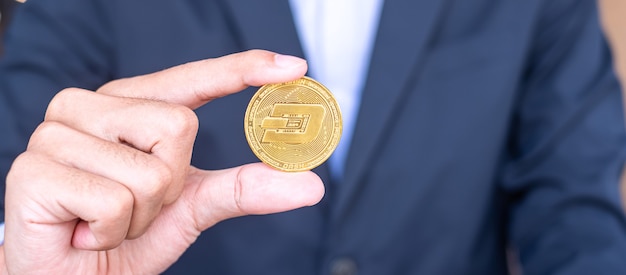Main d'homme d'affaires tenant une pièce de monnaie de crypto-monnaie Golden Dash, Crypto est de l'argent numérique au sein du réseau blockchain, est échangé à l'aide de la technologie et de l'échange Internet en ligne. Notion financière