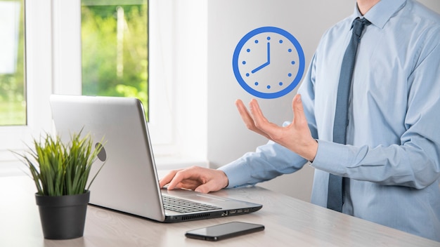 La main de l'homme d'affaires tient l'icône de l'horloge avec la flèche. Exécution rapide du travail. La gestion du temps d'affaires et le temps d'affaires sont des concepts d'argent