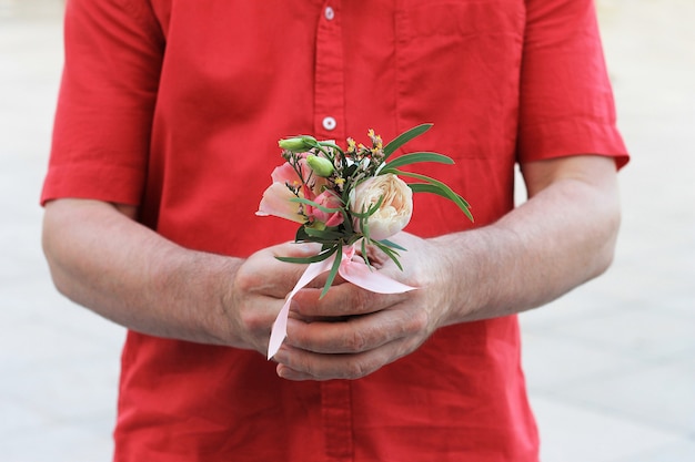 La main d'un homme en chemise rouge tient un beau petit bouquet