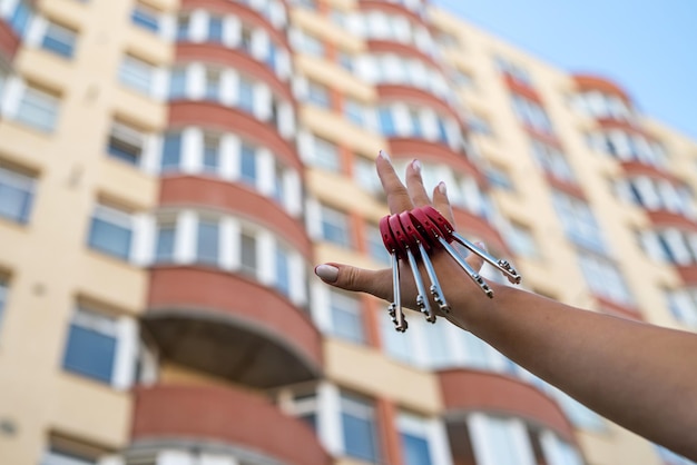 La main de l'homme avec une clé et une maison porte-clés en métal accrochée au côté sur le fond d'une clôture et d'un chalet Projet de construction de déménagement vers une nouvelle maison hypothèque location et achat immobilier