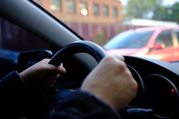 Main d'homme conduisant à l'intérieur de la mise au point sélective de la voiture