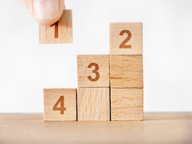 La main de l'homme construisant une pyramide avec quatre cubes de bois avec des numéros par ordre de priorité