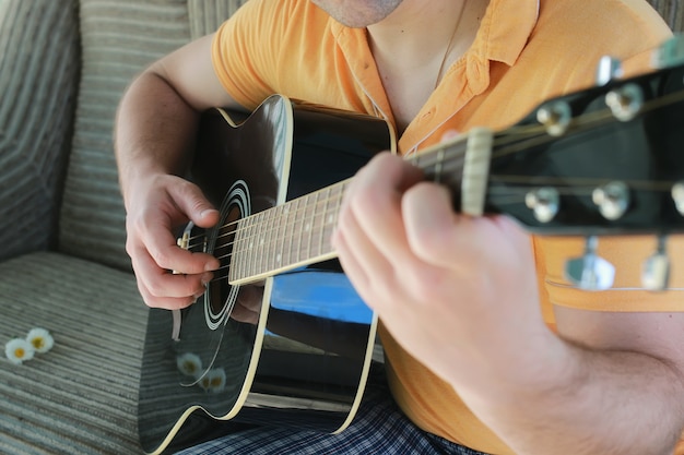 Photo main de l'homme à cordes de guitare en plein air