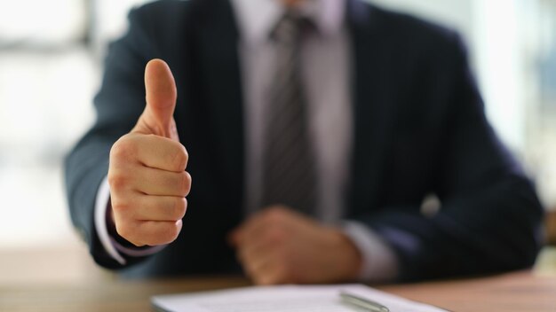 La main de l'homme en costume montre les pouces vers le haut au bureau