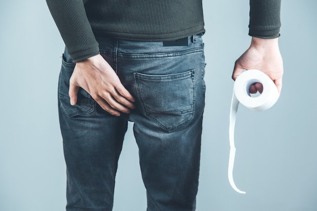 Main de l'homme sur le cul avec du papier toilette