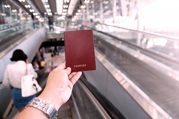 Main de l&#39;homme détenteur d&#39;un passeport à l&#39;aéroport, ton rose en plastique.