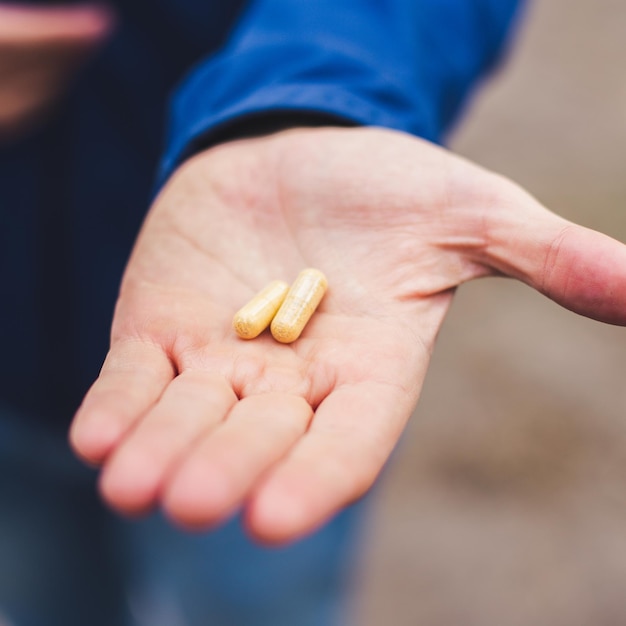 Main d'homme avec deux pilules jaunes. Gros plan des médicaments dans la paume de l'homme