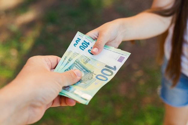 La main d'un homme donne de l'argent à un enfant, centième billets en euros