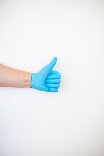 Main d'un homme en gants jetables bleus montre comme sur blanc