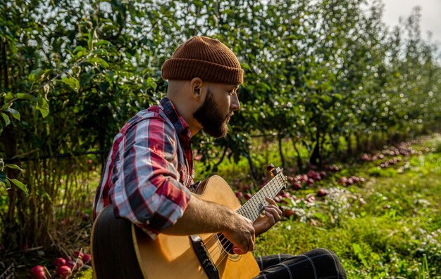 Photo main d'homme jouant une chanson de guitare acoustique arrière-plan de la nature guitares acoustiques homme