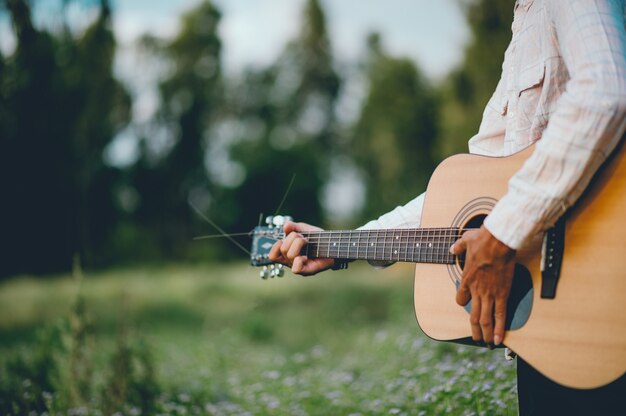 La main de l&#39;homme joue de la guitare acoustique, joue de la guitare dans le jardin seul