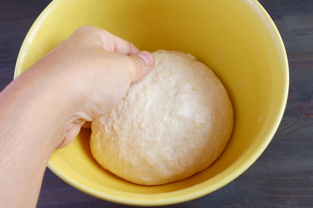 La main de l'homme met la pâte pétrie dans un bol pour la laisser lever avant la cuisson
