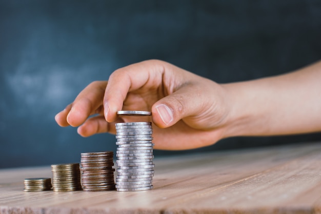 La main de l&#39;homme met des pièces d&#39;argent pour empiler des pièces de monnaie.