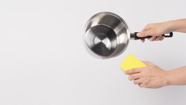 Main d'homme de nettoyage de pot sur fond blanc nettoyant le pot antiadhésif