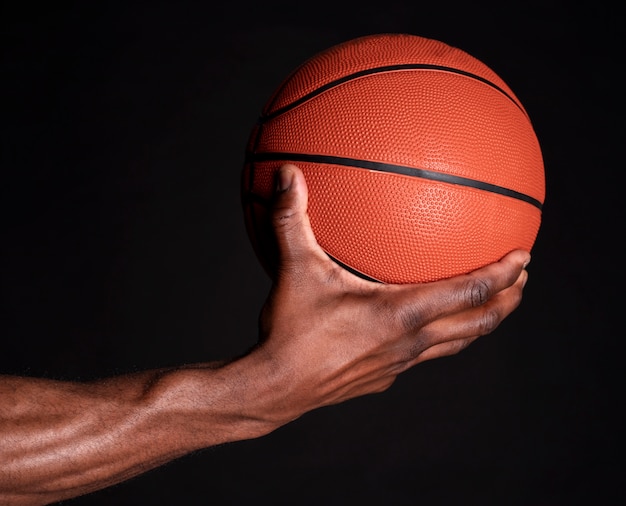 Main de l'homme noir tient le ballon de basket