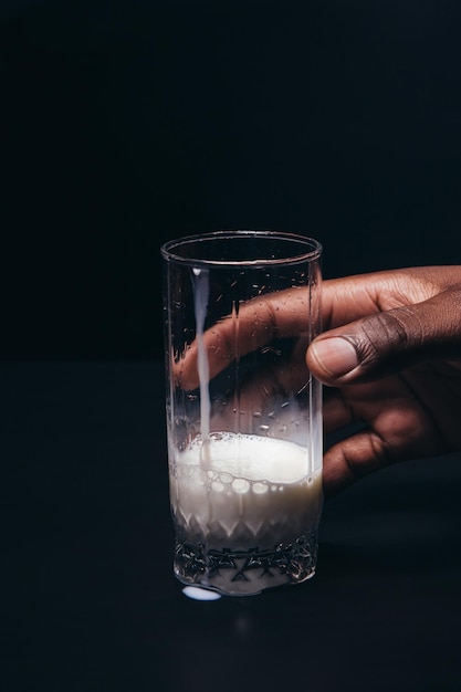 La main de l'homme noir tient un verre de lait blanc