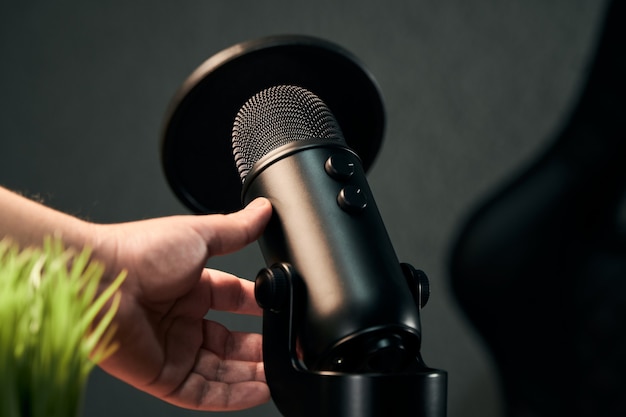 Photo main d'un homme sur le point de prendre un microphone noir sur un gris foncé