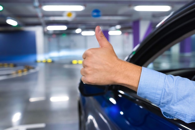 Photo une main d'homme avec un pouce en l'air à l'extérieur d'une voiture dans un parking